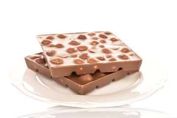 Two bars of dark chocolate with nuts on a white ceramic saucer, close-up, isolated on white.