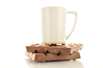 Two bars of dark chocolate with nuts with a white ceramic cup, close-up, isolated on white.