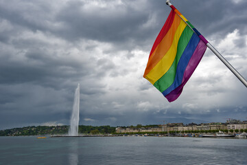 Rainbow flag, a symbol for the LGBT community, waving in the wind with a cloudy background in the Geneva harbor, Switzerland
