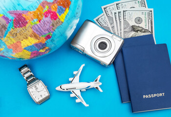Vacations and travelling concept. Model of airplane with globe, watch, passports and money on blue background. Top view.