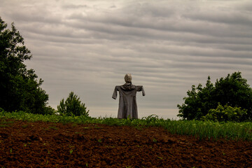 scarecrow in the garden against the backdrop of a cloudy gloomy sky