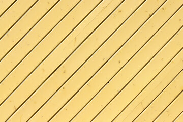 An edge siding wall made of painted in yellow panels with multiple knots as a background