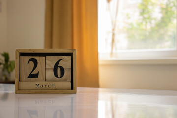 Wooden blocks of the calendar represents the date 26 and the month of March on the background of a...