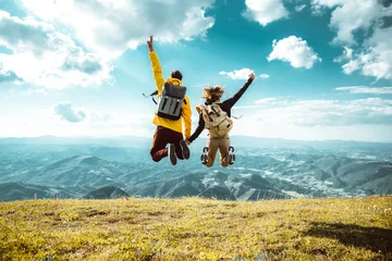 Deurstickers Dolomieten Hikers with backpacks jumping with arms up on top of a mountain - Couple of young happy travelers climbing the peak - Family, travel and adventure concept
