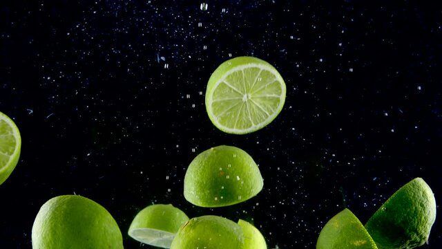 Stock video

Lime splashing into the water in slow motion. Lots of limes falling slowly on a black background. Organic green citrus isolated on black background. Fresh water with fruits.