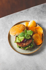 Homemade open beef burger with vegetables on a light concrete background.