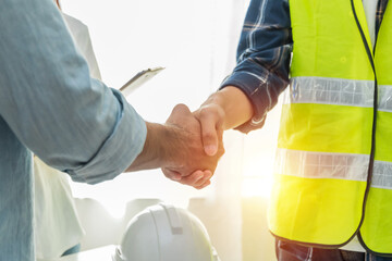 Contractor. construction worker team hands shaking after plan project contract on workplace desk in...