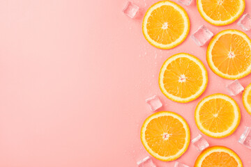 Top view photo of orange slices ice cubes and water drops on isolated pastel pink background with blank space