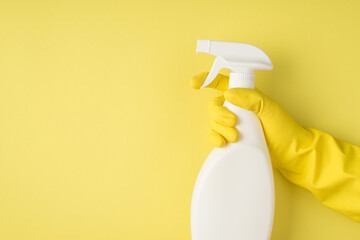 Top view photo of hand in yellow rubber glove using spay detergent white bottle without label on isolated yellow background with blank space - obrazy, fototapety, plakaty