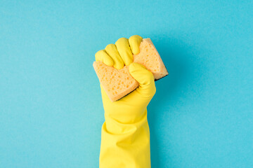 Top view photo of raised hand in yellow rubber glove clenching yellow scouring pad on isolated...