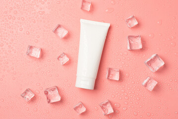 Top view photo of white tube without label ice cubes and drops on isolated pastel pink background with blank space