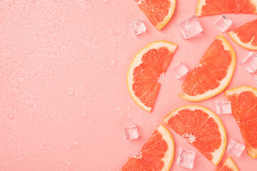 Top view photo of half slices grapefruit ice cubes and water drops on isolated pastel pink...