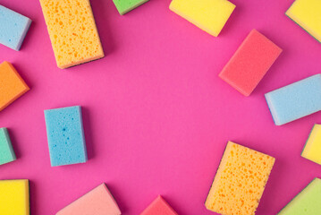 Top view photo of multicolor sponges on isolated pink background with copyspace in the middle