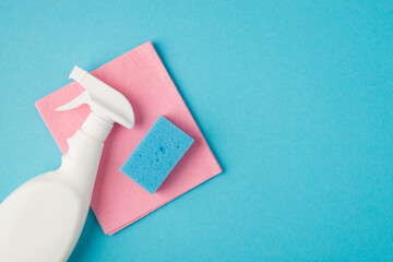 Above photo of pink cleaning rag spray and blue cellulose sponge isolated on the blue background