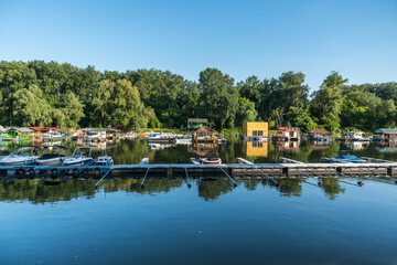 Fototapeta na wymiar View of a floating summer houses intended for summer vacation with berths and a dock for boats and speedboats on the water surface of a river or lake