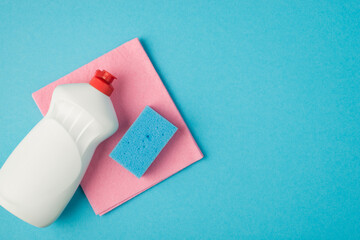 Overhead photo of pink cleaning rag detergent and blue cellulose sponge isolated on the blue background
