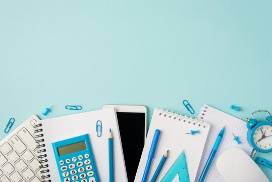 Top view photo of blue stationery copybooks keyboard mouse calculator pencils pens ruler alarm clock smartphone pins and clips on isolated pastel blue background with blank space