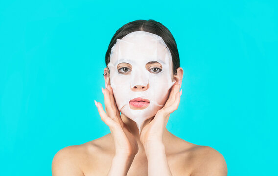 Beautiful woman with beauty mask. Skin care and beauty concept. Moisturizing mask. Anti aging procedure. Woman applying sheet mask on her face, on blue background