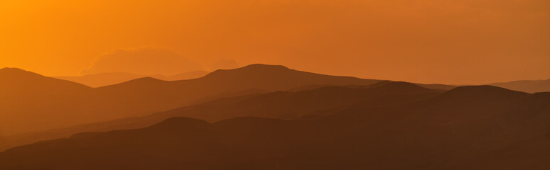 Panorama of mountain ridges silhouettes at sunset