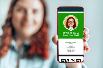 Coronavirus person hand holding smartphone with digital health passport app for travel during covid-19 pandemic.