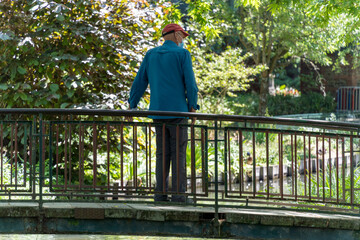 Fototapeta premium Man from behind admiring the scenery on a bridge, overlooking the river