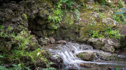 Water flowing along the stones covered with moss in the middle of nature, in spring