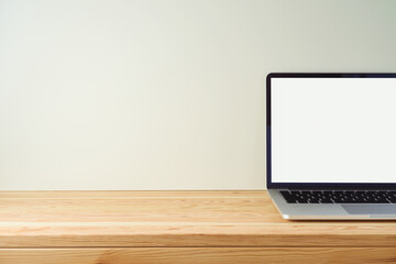 Empty wooden table with laptop computer over white wall background. Mock up for design and product display