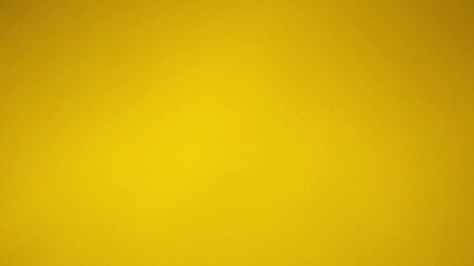 Beautiful gold confetti falling against a yellow background. Christmas, new year, birthday celebration, carnival, anniversary, wedding, glamour party concept. Blurry background, 4k with copy space. - Powered by Adobe