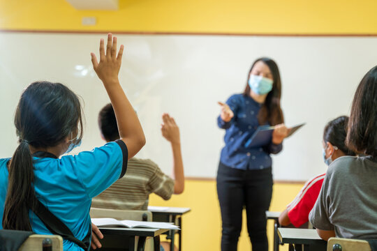 Asian teacher and the back of student having a lesson with face mask back at school after covid-19 quarantine and lockdown.