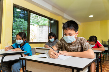 Group of asian children studying in classroom with face mask back at school after covid-19 quarantine and lockdown.