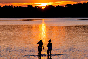 Fototapeta premium People are having fun in a lake under sunset 