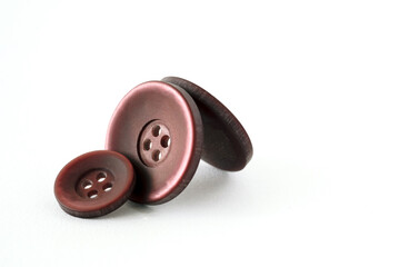 Buttons for clothing, with holes, made of plastic burgundy color on a white background. Sewing accessories. Elements of fashion design.