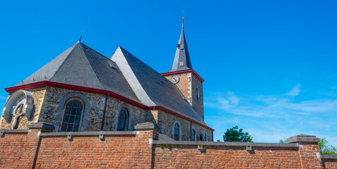 Trees and an old church in sunlight and shadow in green woodland in springtime, Voeren, Limburg, Belgium, June, 2021