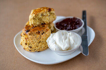 Scones with jam and cream on white plate