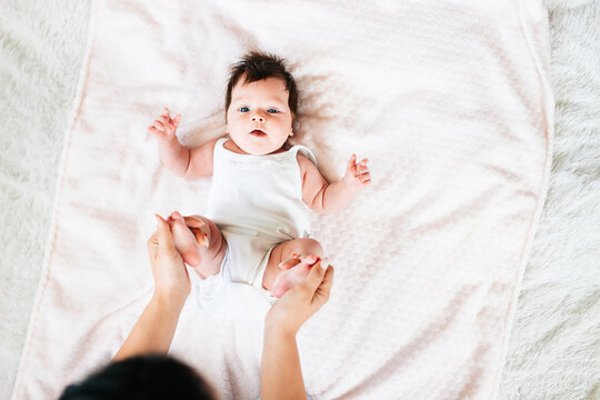 Mom does gymnastics for a newborn baby. Mother and newborn baby. The first month of the mother and child's life at home. The image of a happy motherhood and family