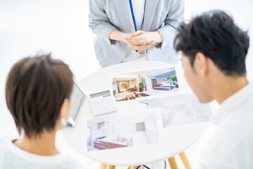 夫婦に不動産を営業するスーツ姿の女性