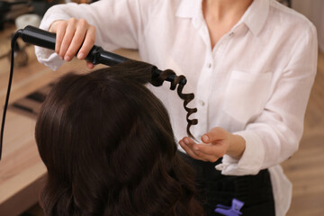 Fototapeta premium Stylist working with client in salon, making hairstyle
