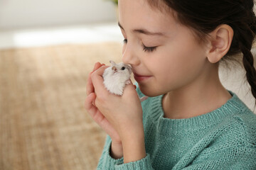 Little girl with cute hamster at home. Space for text