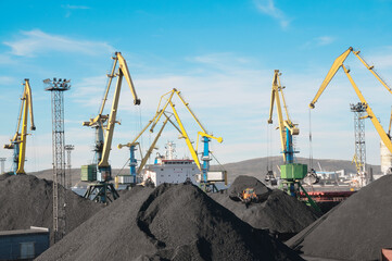 Mountains of coal on the territory of the Murmansk Commercial Sea Port. The unloading of wagons with coal and the loading of this coal into industrial sea ships are going all day and night.