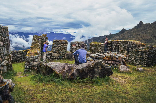 Back view of three male friends contemplating the majestic Phuyupatamarca ruins on Inca trail to Machu Picchu archaeological site from the Inca's ancient civilization in Peru. South America