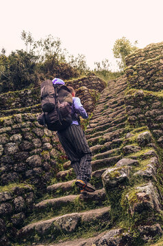 Low view from the back of a backpacker going up stairs on Phuyupatamarca ruins. Inca trail to Machu Picchu archaeological site from the Inca's ancient civilization in Peru. South America