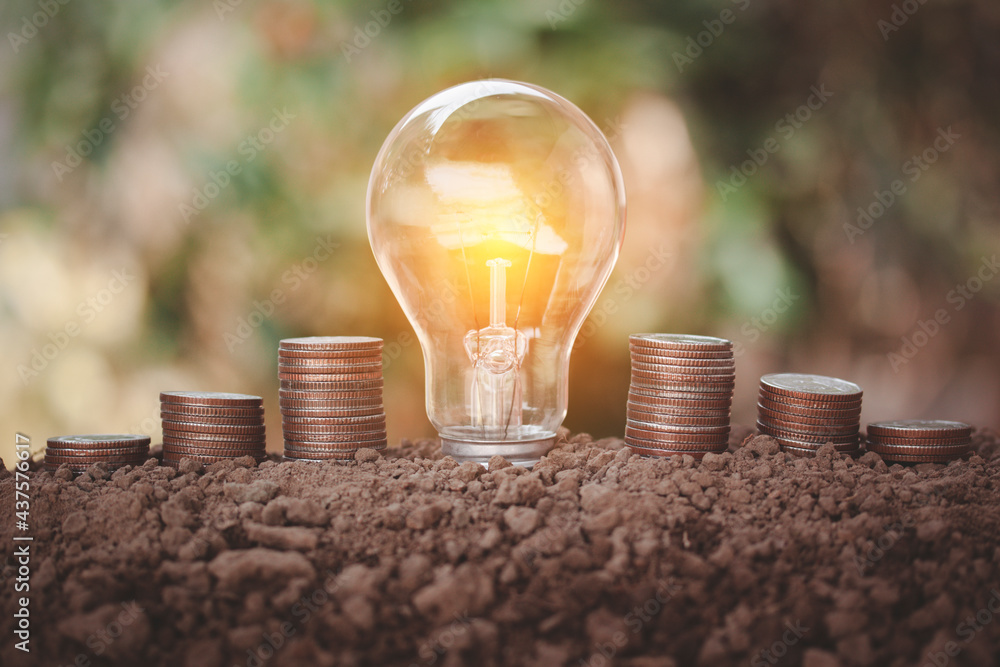 Poster energy saving light bulb in the midle of coin stackign on soil to show step of saving energy saving 