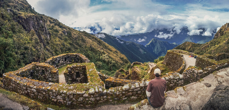 High angle panoramic view of a man contemplating the huge valley in front of him on Phuyupatamarca ruins. Inca trail to Machu Picchu archaeological site in Peru. South America
