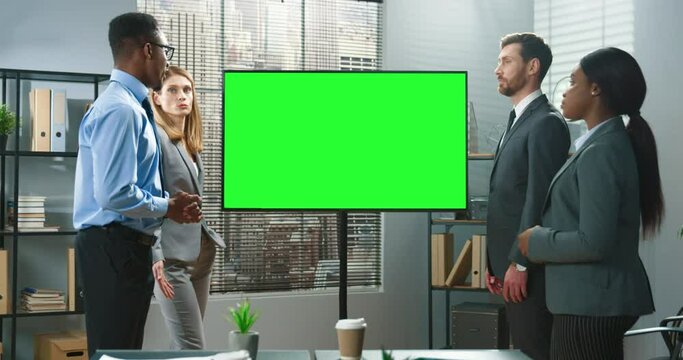 Working process. Serious successful team of the business people peeping at the projector screen while their male colleague explaining something to them. Work process concept