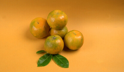 Fresh orange citrus fruit with leaves isolated on yellow background. Juicy and sweet and renowned...