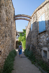Fototapeta na wymiar Femme touriste promenant sous les arceaux d'une ruelle du village de Cliouscat dans la Drôme