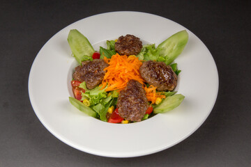 turkish meatball köfte service and salad 

white plate black background
