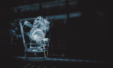 Ice cube in an empty glass on a bar counterin bar or pub