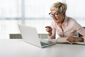 Happy senior woman working on laptop in the office