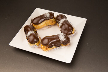 eclairs chocolate sweet food white plate 

black background